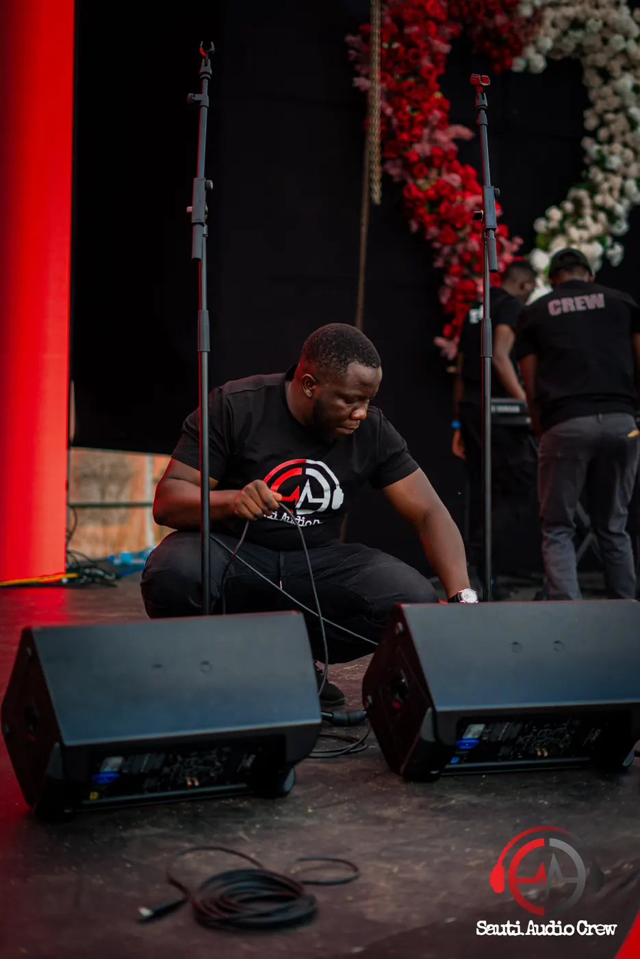 Sauti crew member positioning stage monitors before a show