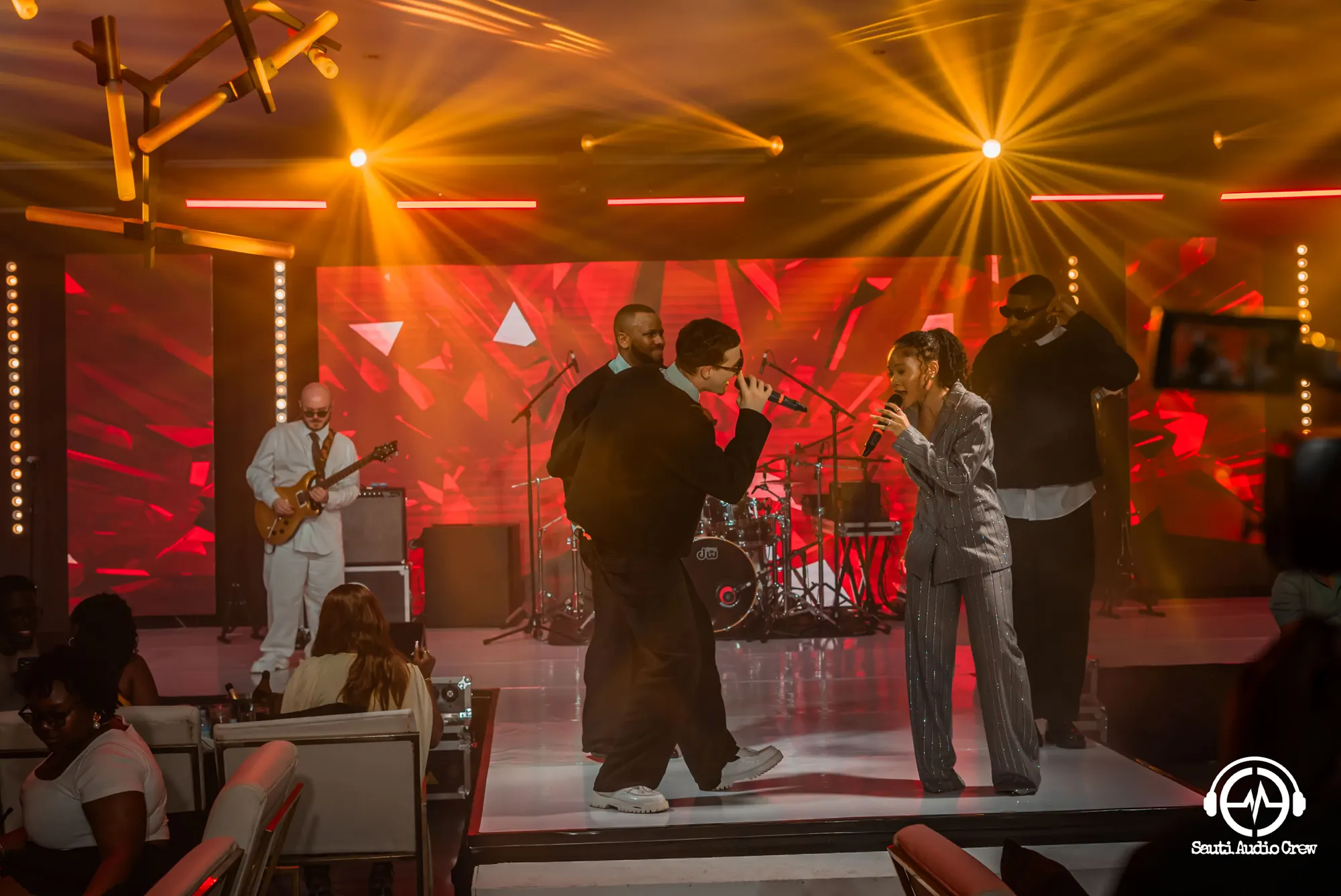 Live band performing under golden stage beams at a Sauti-powered show