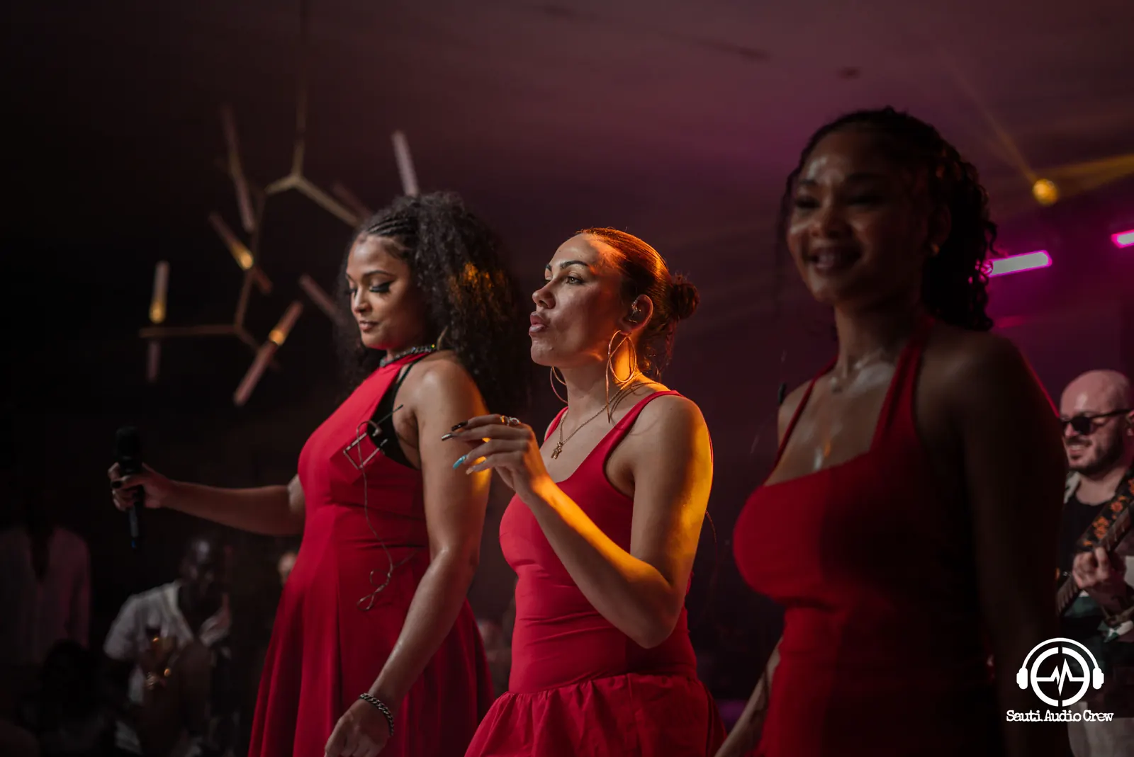 Backing vocalists in red singing to the crowd
